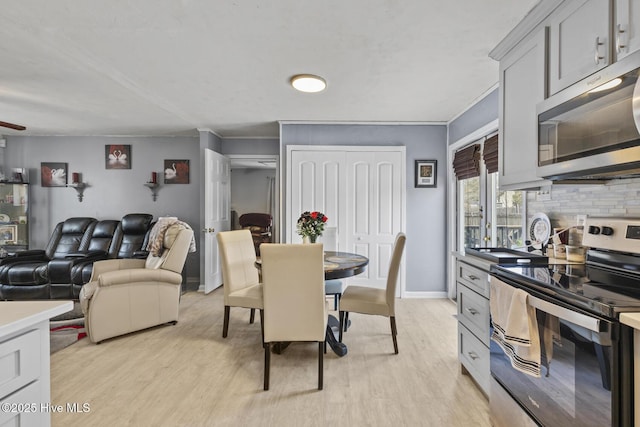 dining space featuring light wood-style floors, baseboards, and ornamental molding