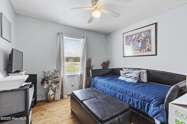 bedroom featuring baseboards, a textured ceiling, light wood-style flooring, and a ceiling fan