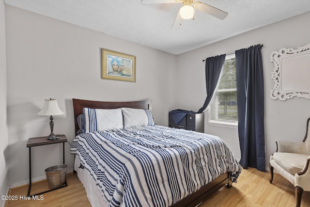 bedroom featuring baseboards, a textured ceiling, ceiling fan, and wood finished floors