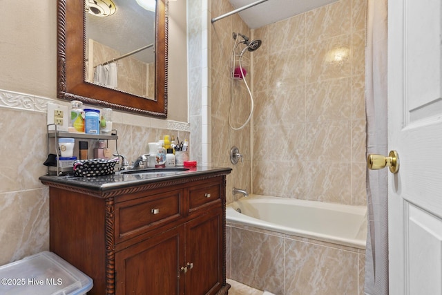 bathroom with tile walls, vanity, and tiled shower / bath