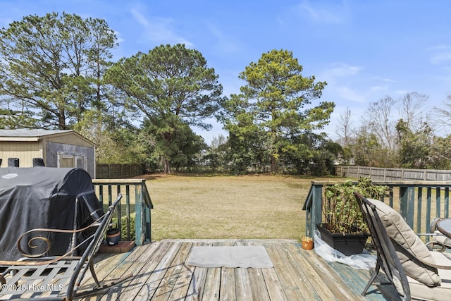 wooden deck featuring grilling area, a lawn, a fenced backyard, and an outdoor structure