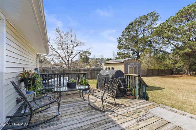 deck with a storage unit, an outbuilding, a lawn, and a fenced backyard