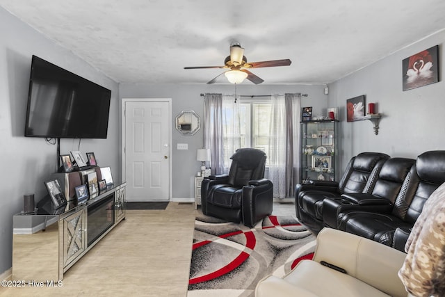 living room featuring baseboards, light wood-style flooring, and a ceiling fan