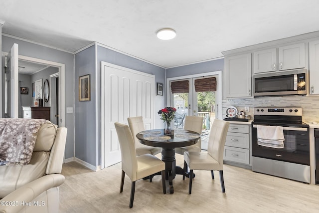 dining room with baseboards, light wood finished floors, and ornamental molding