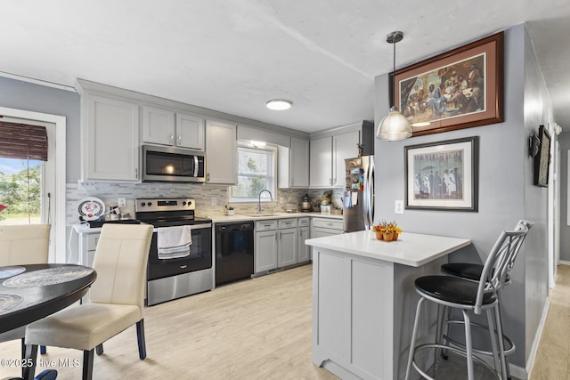 kitchen featuring decorative backsplash, appliances with stainless steel finishes, light countertops, and a sink