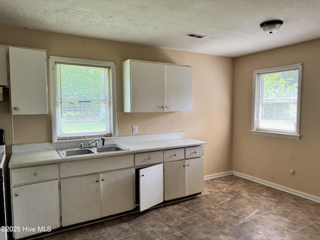 1122 E Stewart Cir, Wilmington, NC 28405 - kitchen featuring a sink, light countertops, a textured ceiling, baseboards, and white cabinets