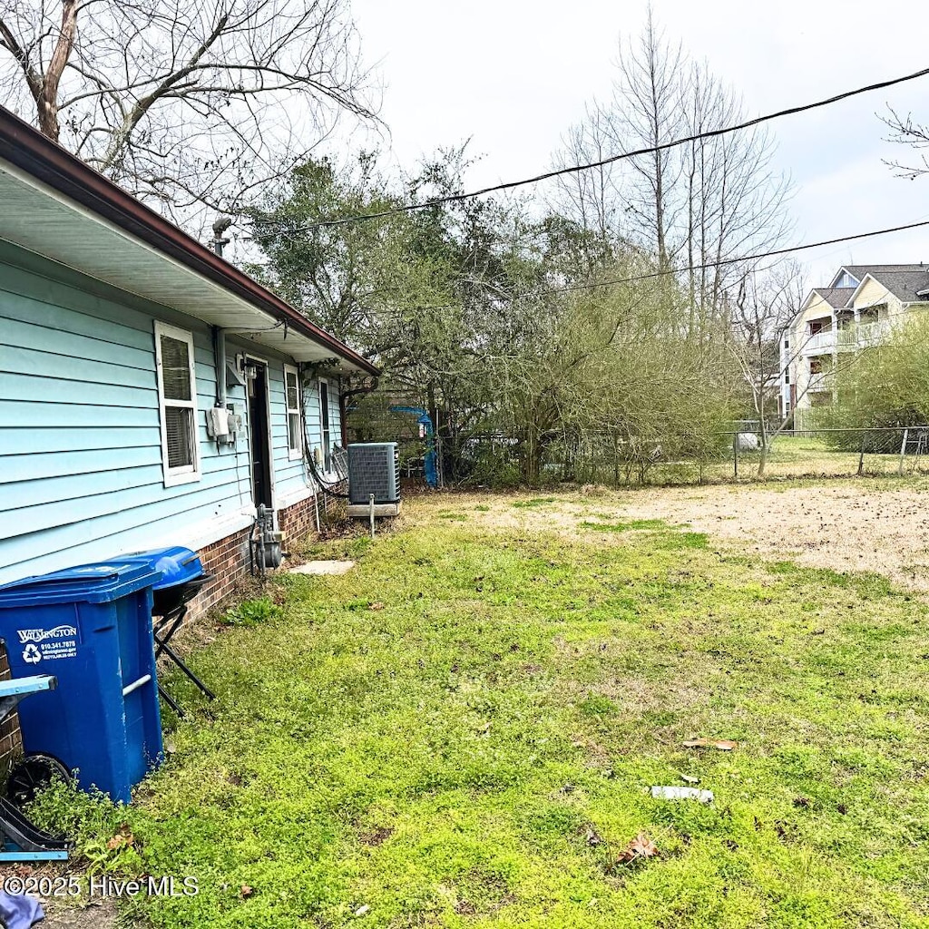 view of yard featuring central AC and fence