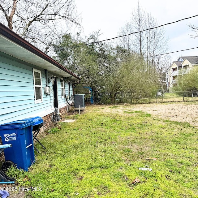 view of yard featuring central AC and fence