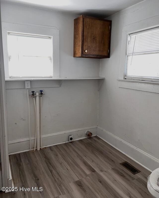 laundry room with hookup for a washing machine, cabinet space, wood finished floors, and visible vents