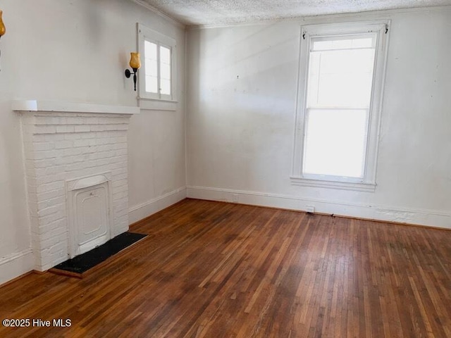 unfurnished living room with hardwood / wood-style floors, baseboards, and a textured ceiling