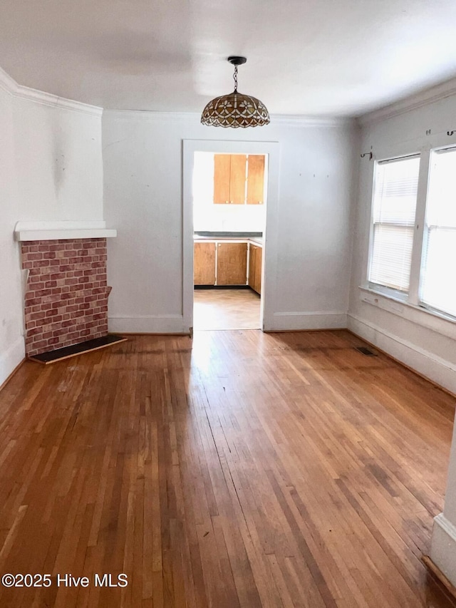 unfurnished living room with hardwood / wood-style floors, baseboards, and ornamental molding