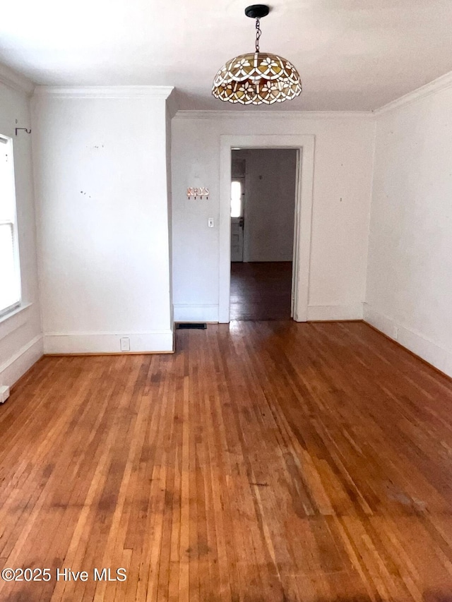 empty room featuring wood-type flooring, baseboards, and ornamental molding