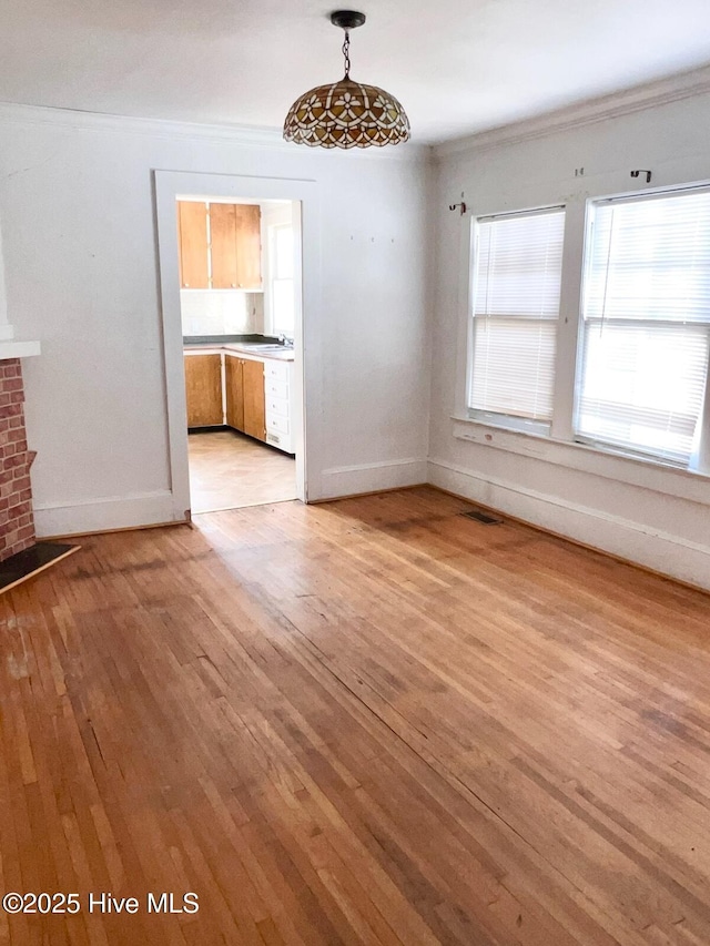 interior space with light wood finished floors, visible vents, crown molding, and baseboards