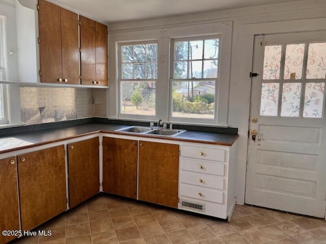 kitchen featuring dark countertops, brown cabinets, and a sink