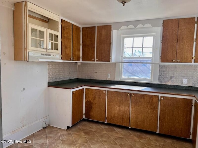 kitchen featuring tasteful backsplash, dark countertops, brown cabinetry, and extractor fan