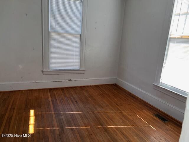 unfurnished room featuring visible vents, baseboards, and wood finished floors