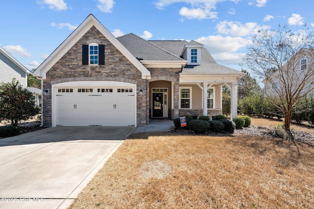 view of front of property featuring roof with shingles, a porch, concrete driveway, a garage, and stone siding