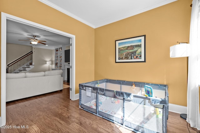 living room with a ceiling fan, crown molding, wood finished floors, and baseboards