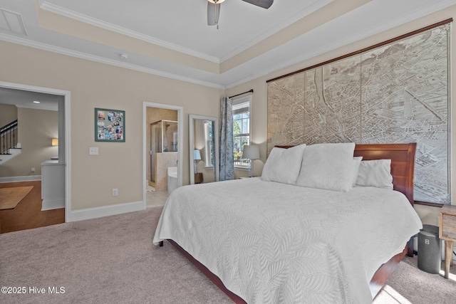 bedroom featuring a tray ceiling, carpet flooring, baseboards, and ensuite bathroom