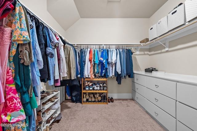 walk in closet with light colored carpet and lofted ceiling