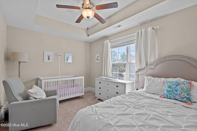 bedroom with visible vents, baseboards, ceiling fan, carpet flooring, and a raised ceiling