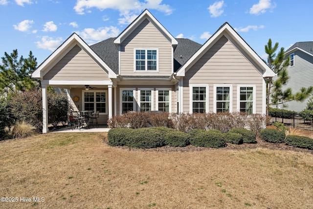 rear view of house featuring a ceiling fan, a patio, fence, a yard, and roof with shingles