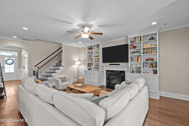 living area featuring visible vents, arched walkways, wood finished floors, and a ceiling fan