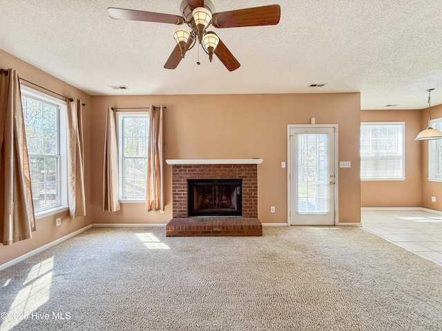 unfurnished living room featuring visible vents, carpet flooring, a fireplace, and a textured ceiling