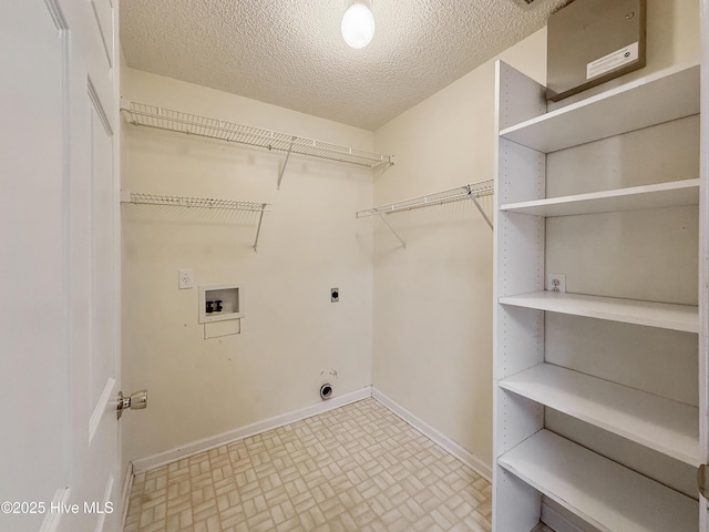 laundry area with hookup for a washing machine, baseboards, laundry area, electric dryer hookup, and a textured ceiling