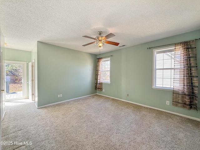 empty room with visible vents, a ceiling fan, a textured ceiling, carpet flooring, and baseboards