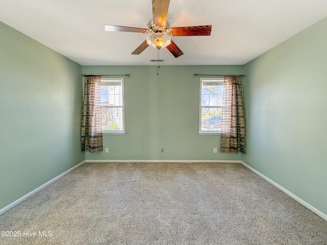 carpeted empty room with a wealth of natural light, visible vents, a textured ceiling, and baseboards