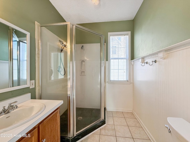 full bath featuring a shower stall, toilet, vanity, tile patterned floors, and a textured ceiling