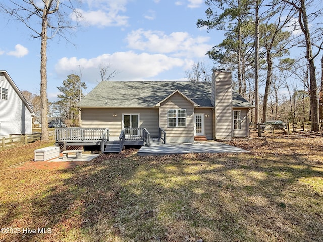 rear view of property featuring a patio, a lawn, a deck, and a chimney