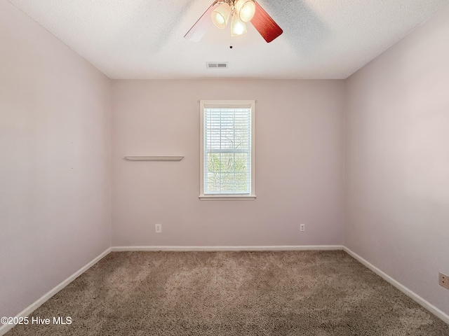 empty room with visible vents, a textured ceiling, carpet, and a ceiling fan