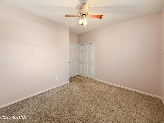 carpeted spare room with ceiling fan and baseboards