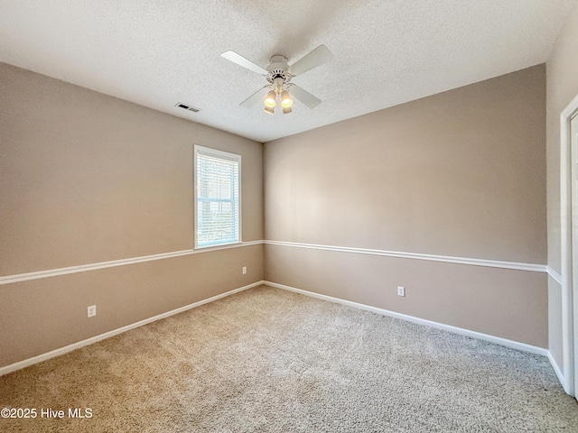 carpeted empty room with visible vents, baseboards, a textured ceiling, and a ceiling fan