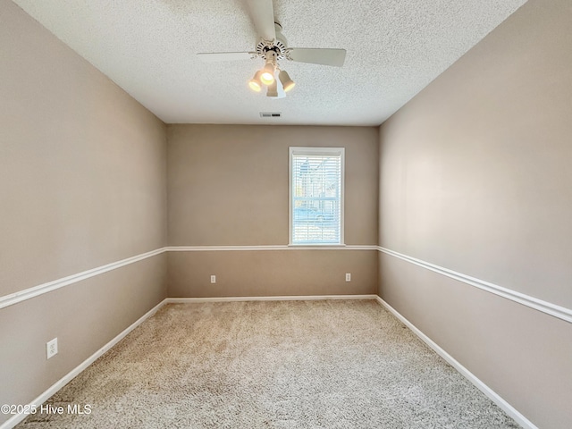 carpeted empty room with ceiling fan, visible vents, baseboards, and a textured ceiling