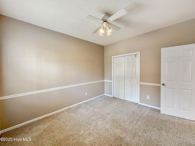 unfurnished bedroom featuring a textured ceiling, a closet, carpet floors, baseboards, and ceiling fan