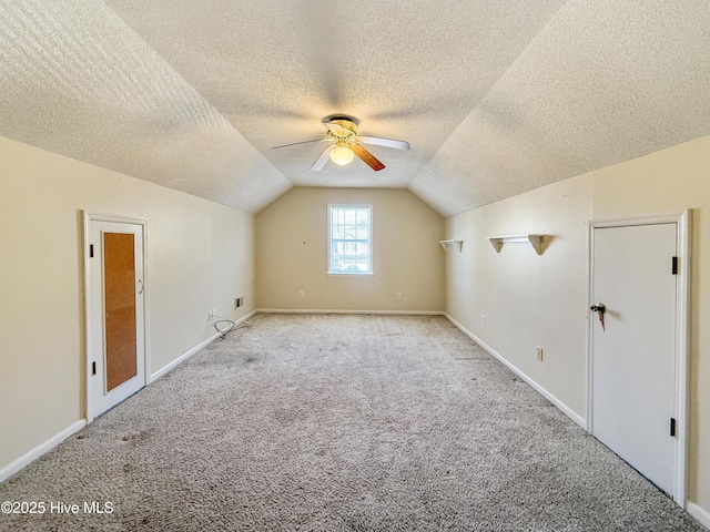 bonus room featuring lofted ceiling, a ceiling fan, a textured ceiling, carpet flooring, and baseboards