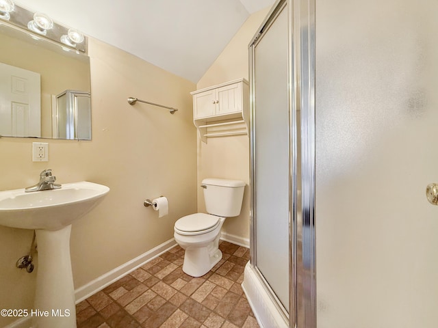 full bathroom featuring stone finish flooring, baseboards, toilet, vaulted ceiling, and a shower with shower door