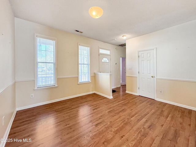 spare room featuring light wood-style floors, visible vents, and baseboards