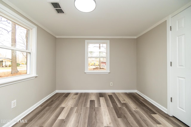 spare room featuring visible vents, baseboards, wood finished floors, and ornamental molding