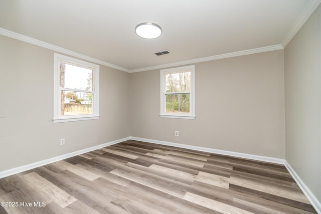 spare room with visible vents, baseboards, a healthy amount of sunlight, and crown molding