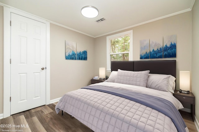 bedroom with crown molding, wood finished floors, visible vents, and baseboards