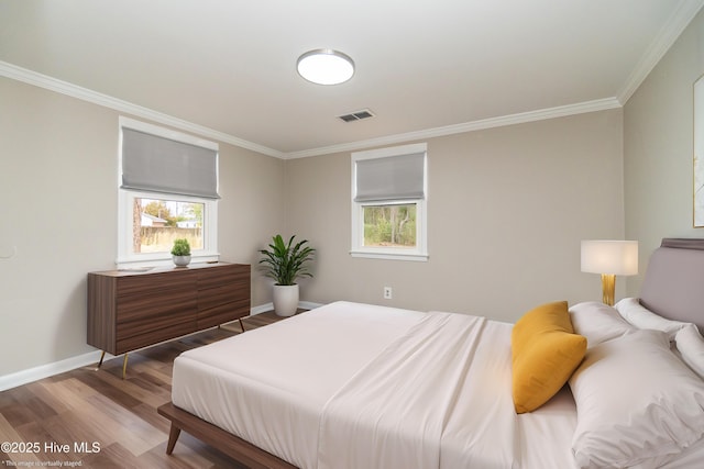 bedroom featuring crown molding, wood finished floors, visible vents, and baseboards