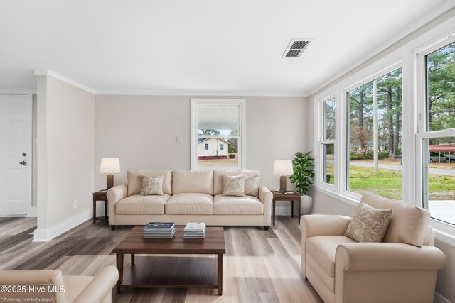 living area with visible vents, ornamental molding, baseboards, and wood finished floors