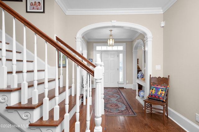 foyer with wood finished floors, crown molding, and arched walkways