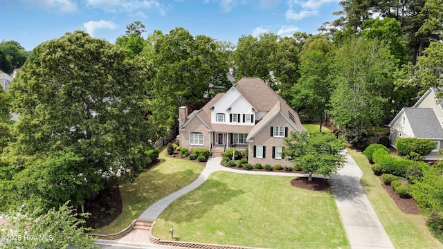 view of front of property featuring a front yard, brick siding, and a chimney