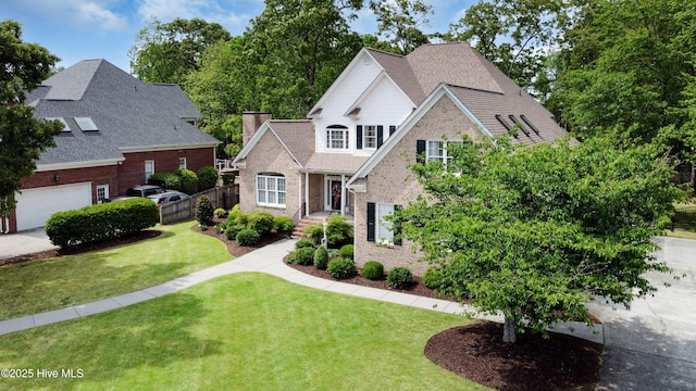 traditional-style home with a garage, brick siding, fence, and a front lawn