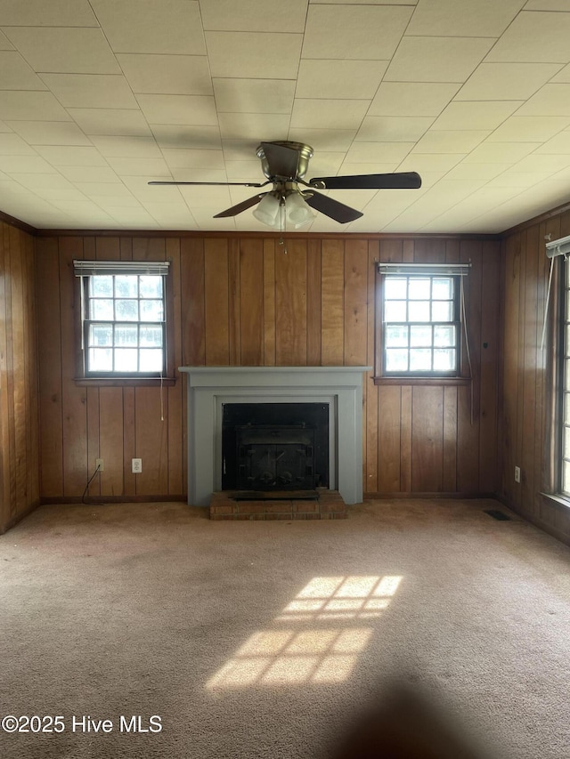 unfurnished living room featuring a wealth of natural light, carpet, and a fireplace with raised hearth